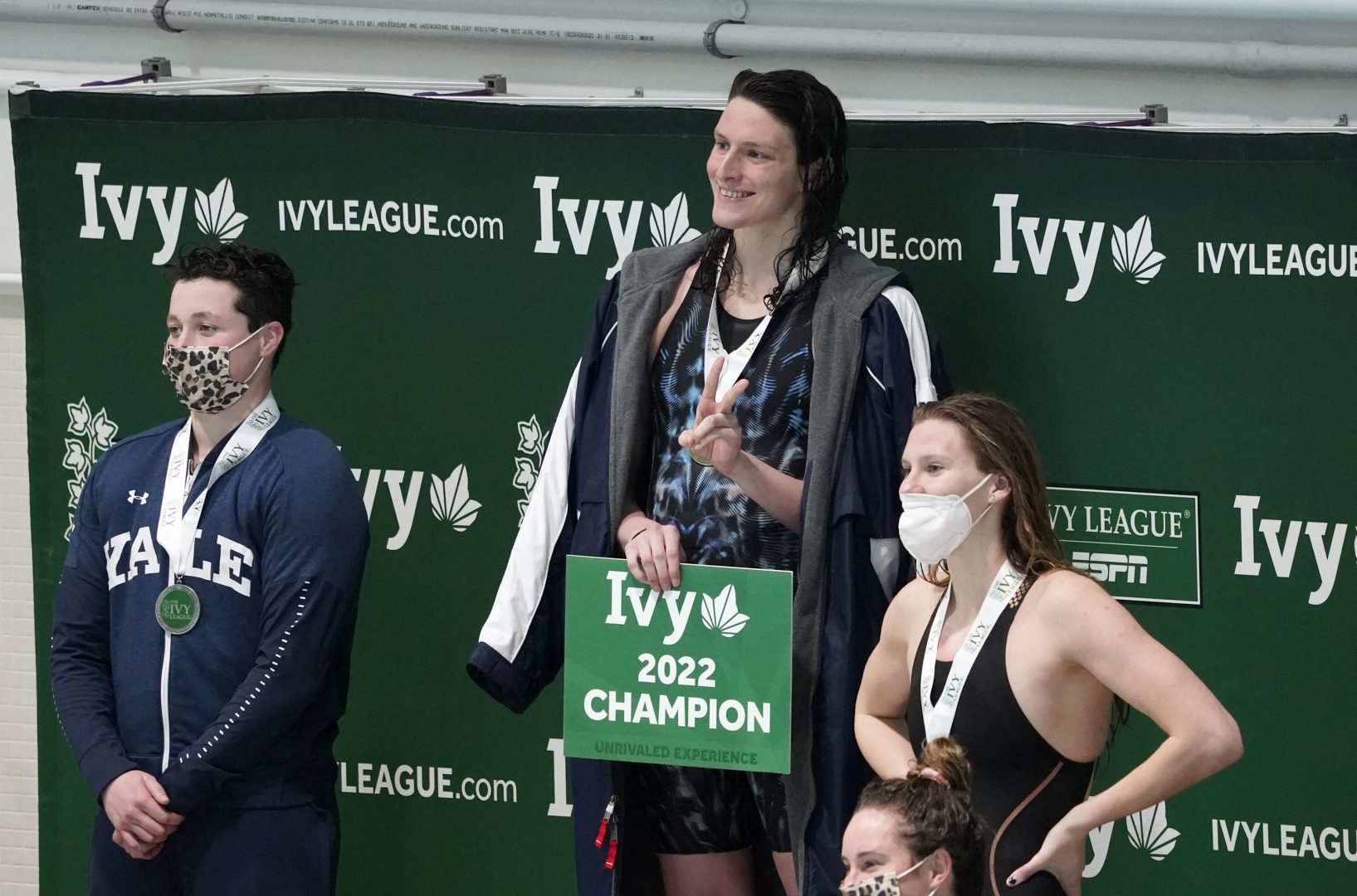 Pennsylvania's Lia Thomas, center, Yale's Iszak Henig, left, and Princeton's Nikki Venema stand on the podium following a medal ceremony after Thomas won the 100-yard freestyle, Henig finished second and Venema third at the Ivy League women's swimming and diving championships at Harvard, Saturday, Feb. 19, 2022, in Cambridge, Mass. Henig, who is transitioning to male but hasn't begun hormone treatments yet, is swimming for the Yale women's team and Thomas, who is transitioning to female, is swimming for the Penn women's team. (AP Photo/Mary Schwalm)