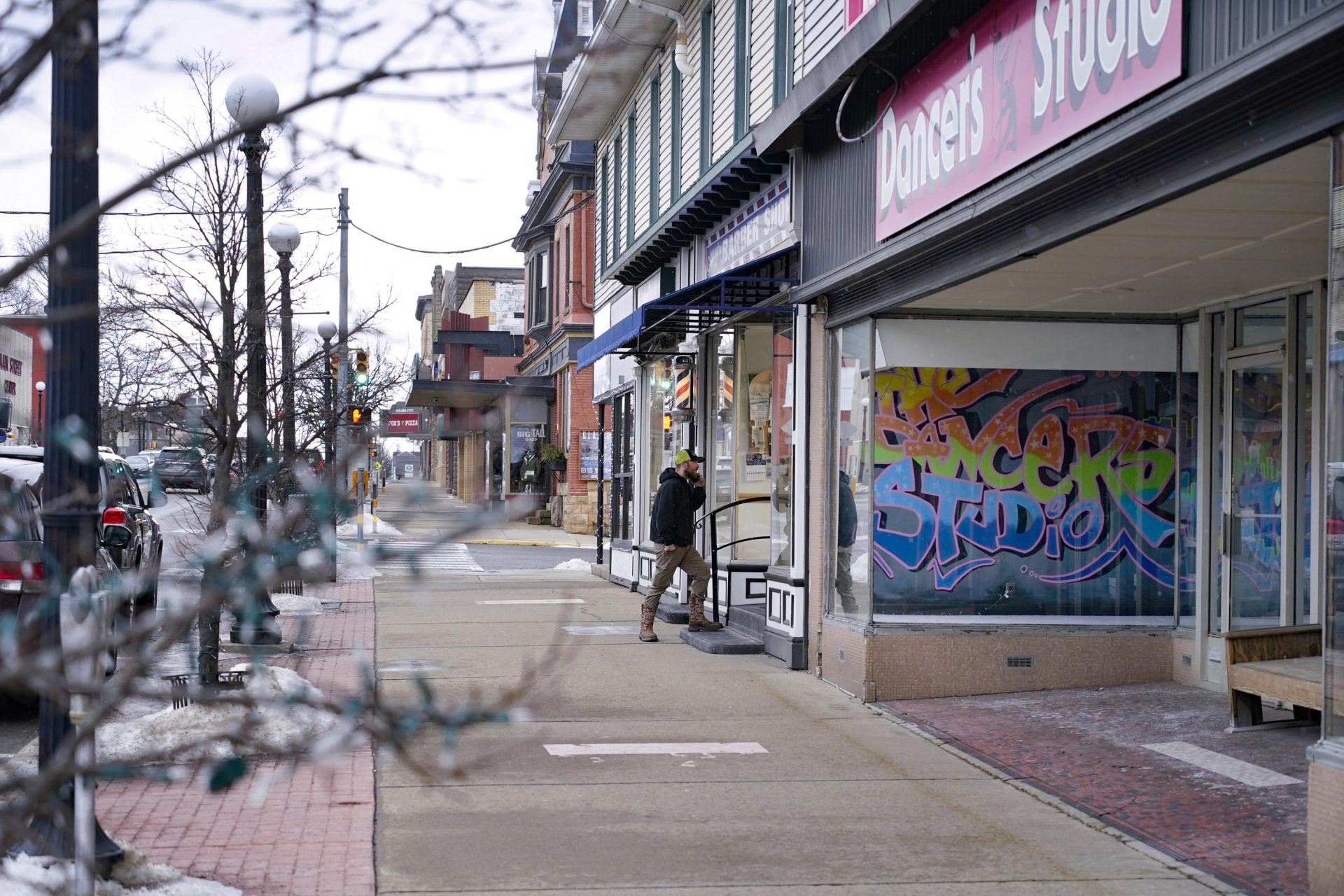 A man talks on his phone as he enters the barber shop along Main Street in Clarion, Pa., Saturday, Feb. 12, 2022.