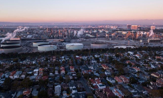 An aerial image taken on January 24, 2022 shows storage tanks at the Chevron Products Company El Segundo Refinery adjacent to a neighborhood of homes at sunset in Manhattan Beach, California. - The oil refinery supplies motor vehicle fuels including gasoline and diesel to Southern California as well as jet fuel for aircraft at Los Angeles International Airport (LAX). (Photo by Patrick T. FALLON / AFP) (Photo by PATRICK T. FALLON/AFP via Getty Images)