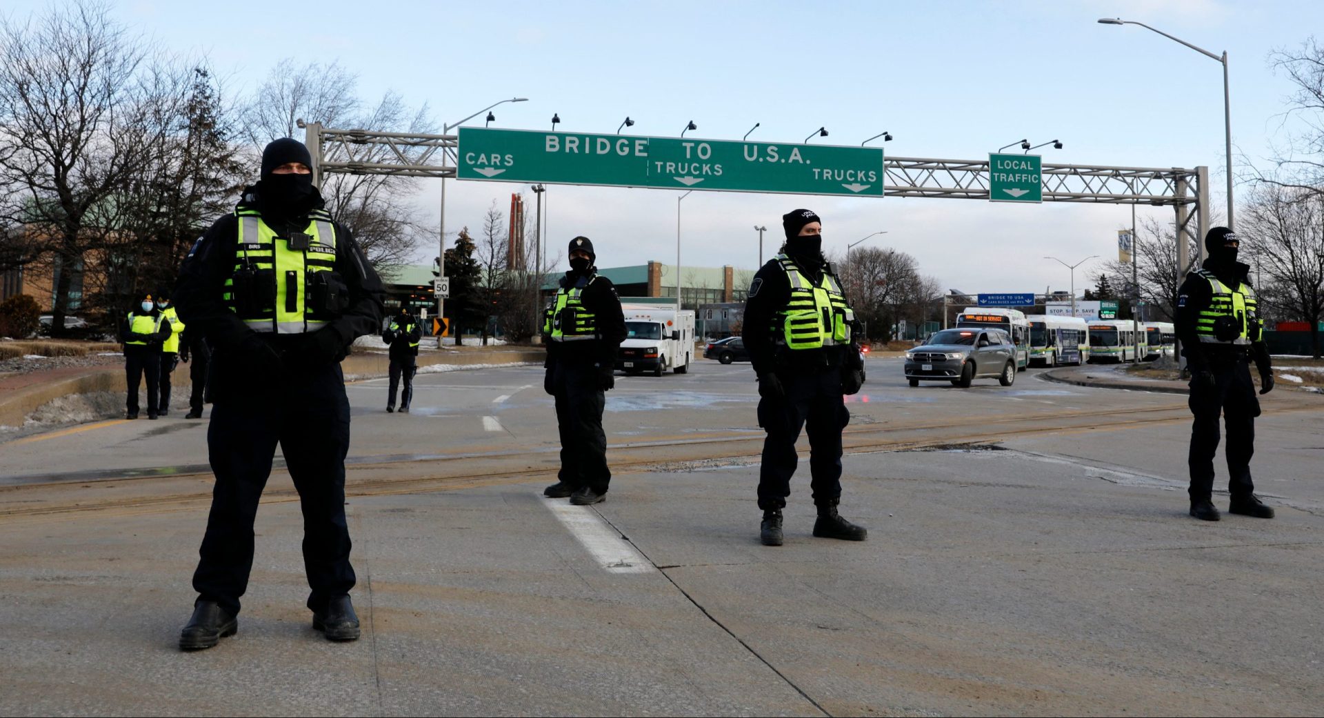 Police from London, Ontario, keep protestors against Covid-19 vaccine mandates from the entrance to the Ambassador Bridge in Windsor, Ontario, Canada, on February 12, 2022. - Police in Canada were positioning Saturday to clear the bridge on the US border, snarled for days by truckers protesting against vaccination rules, an AFP journalist observed. 