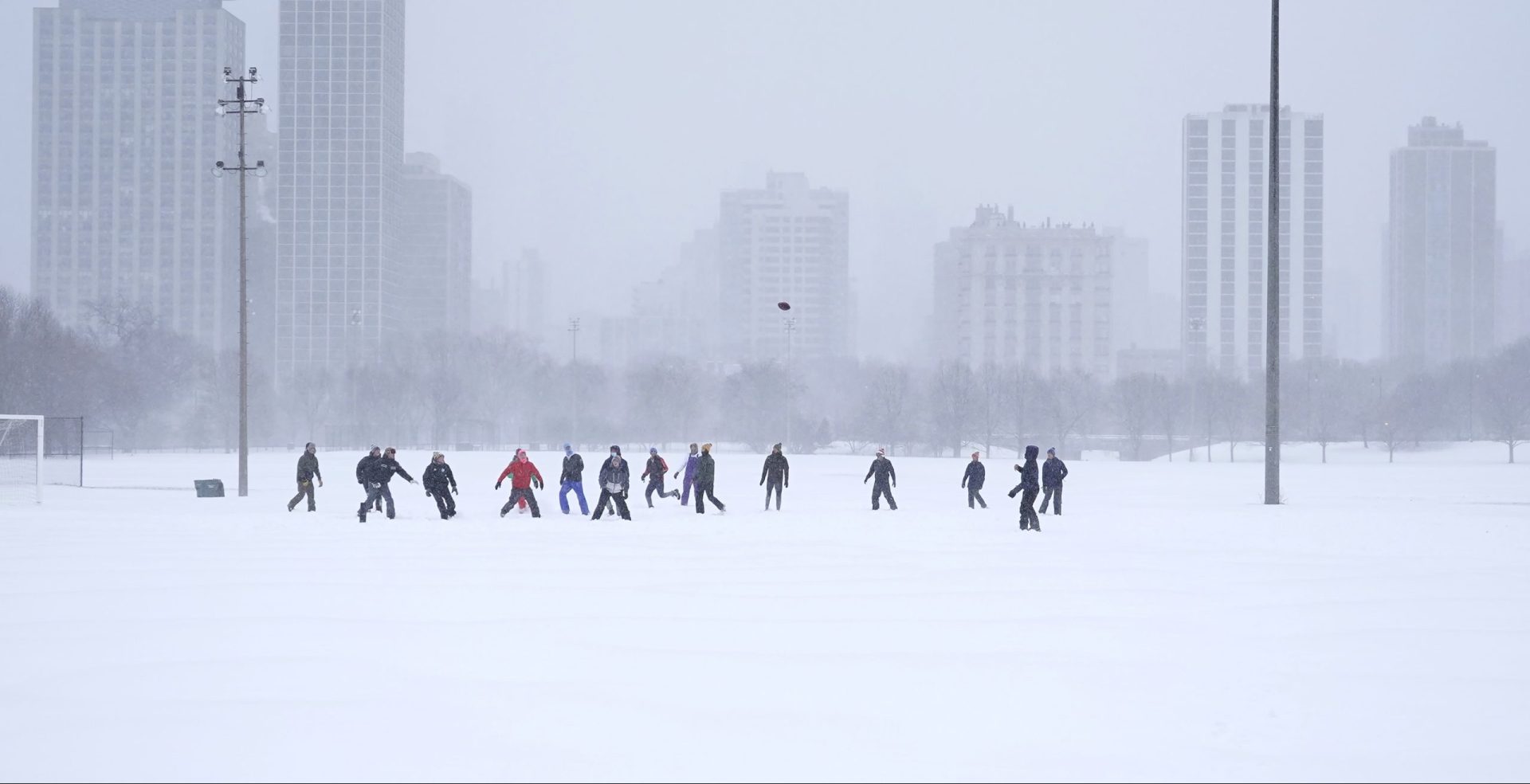 Men play football on a soccer field in Chicago's Lincoln Park Wednesday, Feb. 2, 2022. A major winter storm with millions of Americans in its path brought a mix of rain, freezing rain and snow to the middle section of the United States as airlines canceled hundreds of flights, governors urged residents to stay off roads and schools closed campuses.