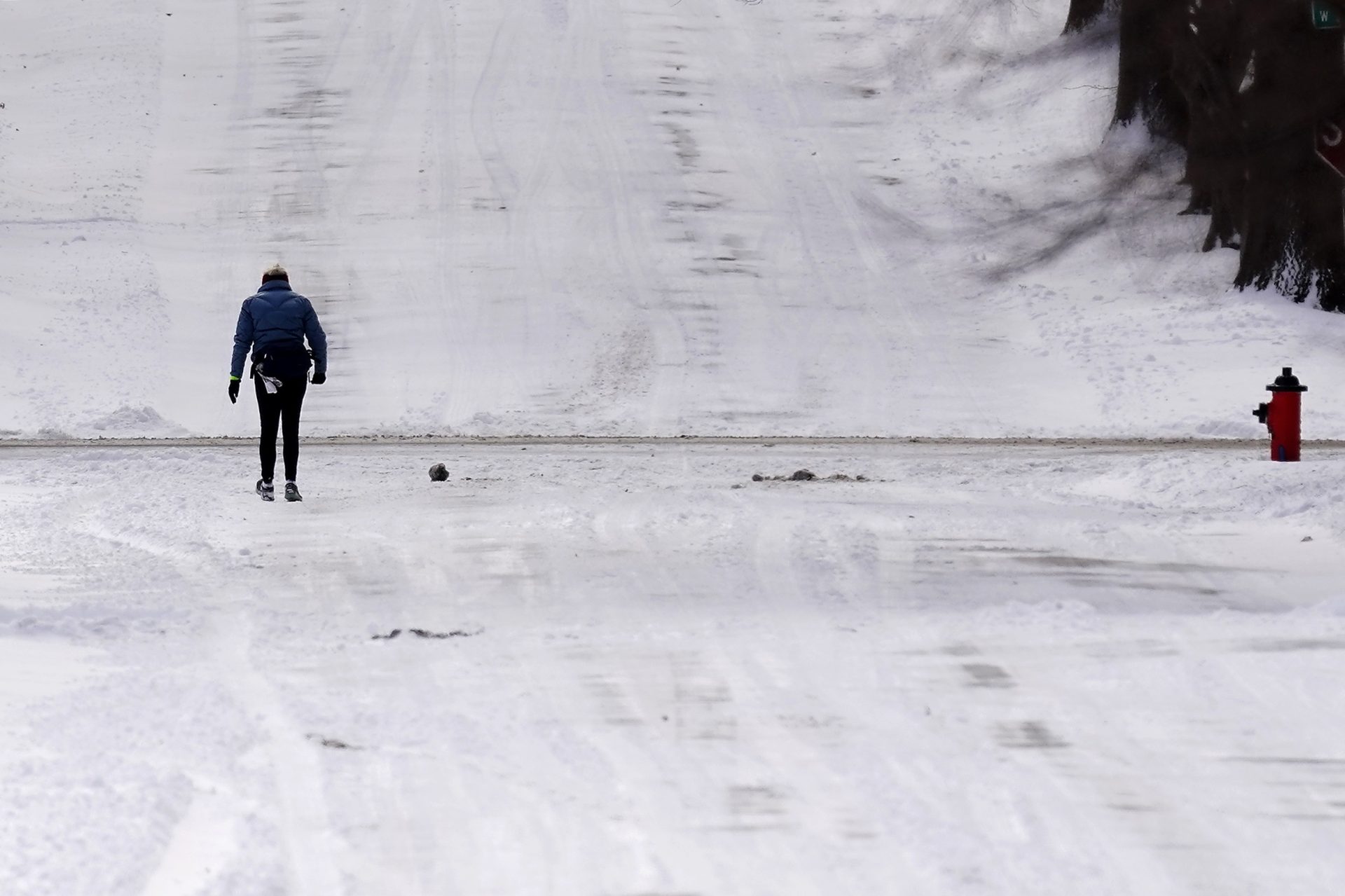 A woman walks down a snow-covered street Wednesday, Feb. 2, 2022, in Kansas City, Mo.