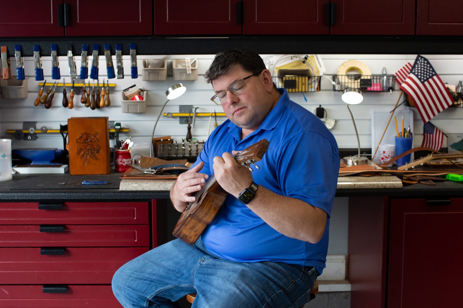Michael Schneider, a retired Marine Corps Master Sergeant, plays a ukulele in his leatherworking studio at his home in Swansboro, North Carolina on February 12, 2022. He uses art and music therapy to help manage his epilepsy and PTSD following a traumatic brain injury. Schneider explains that by playing music, he can literally stop himself from having a seizure by affecting how his brain is functioning.