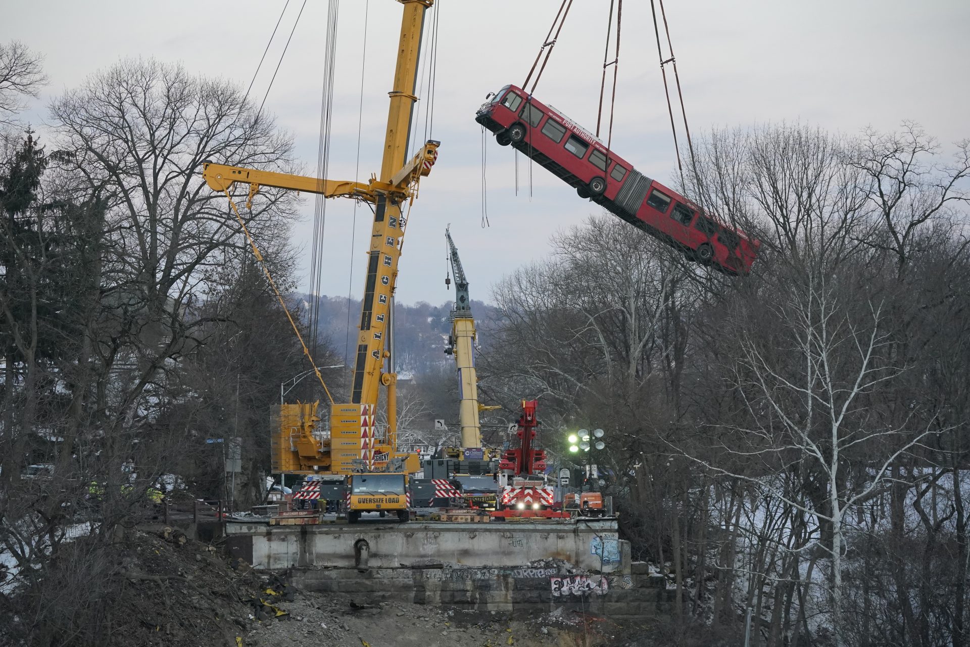 A crane hoists a Pittsburgh Transit Authority bus on Monday Jan. 31, 2022, that was trapped on the Fern Hollow Bridge when it collapsed on Jan 28, 2022.
