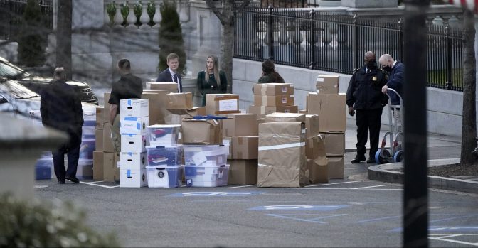 In this Jan. 14, 2021, file photo people wait for a moving van after boxes were moved out of the Eisenhower Executive Office building inside the White House complex in Washington.