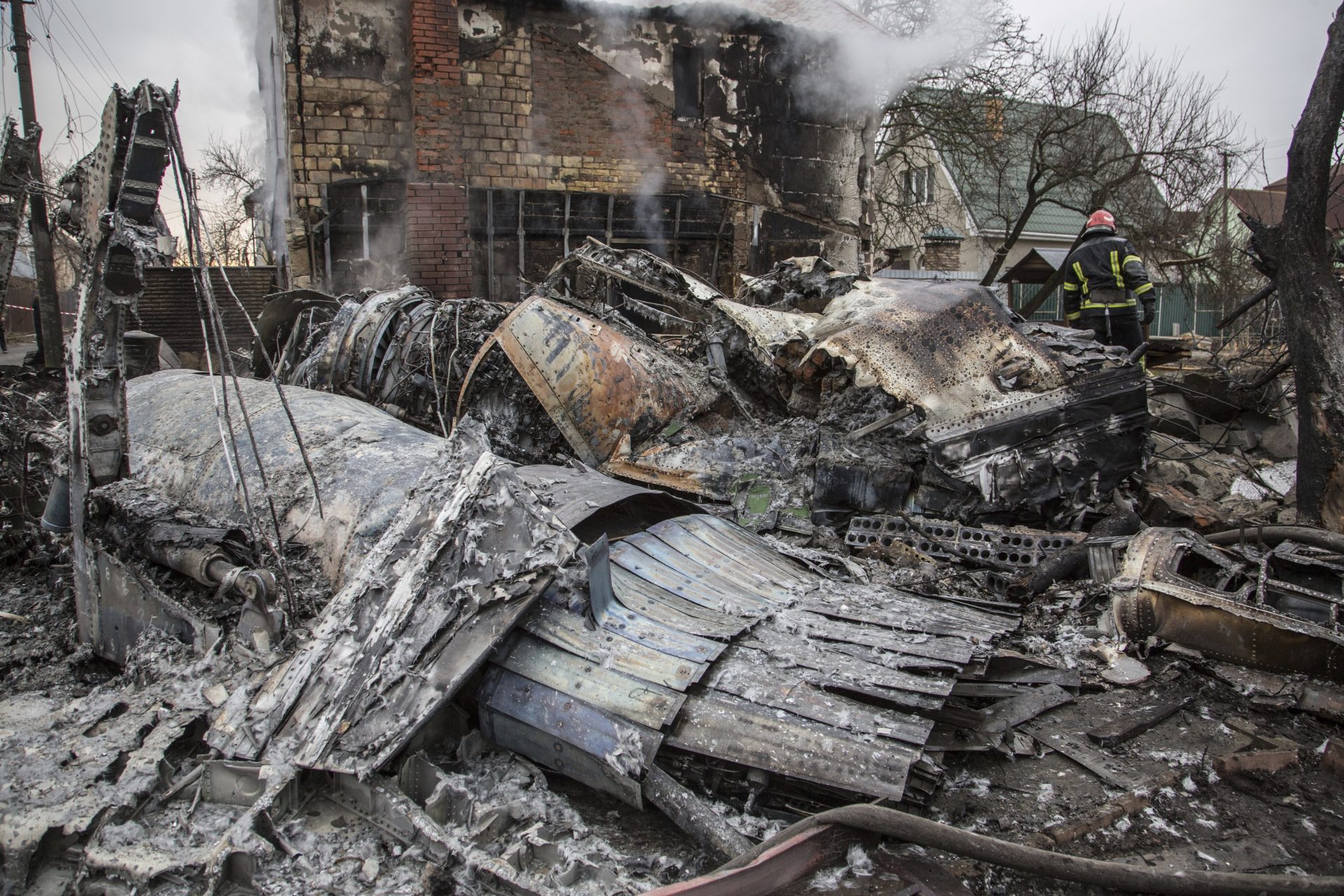 A Ukrainian firefighter walks between at fragments of a downed aircraft seen in in Kyiv, Ukraine, Friday, Feb. 25, 2022.