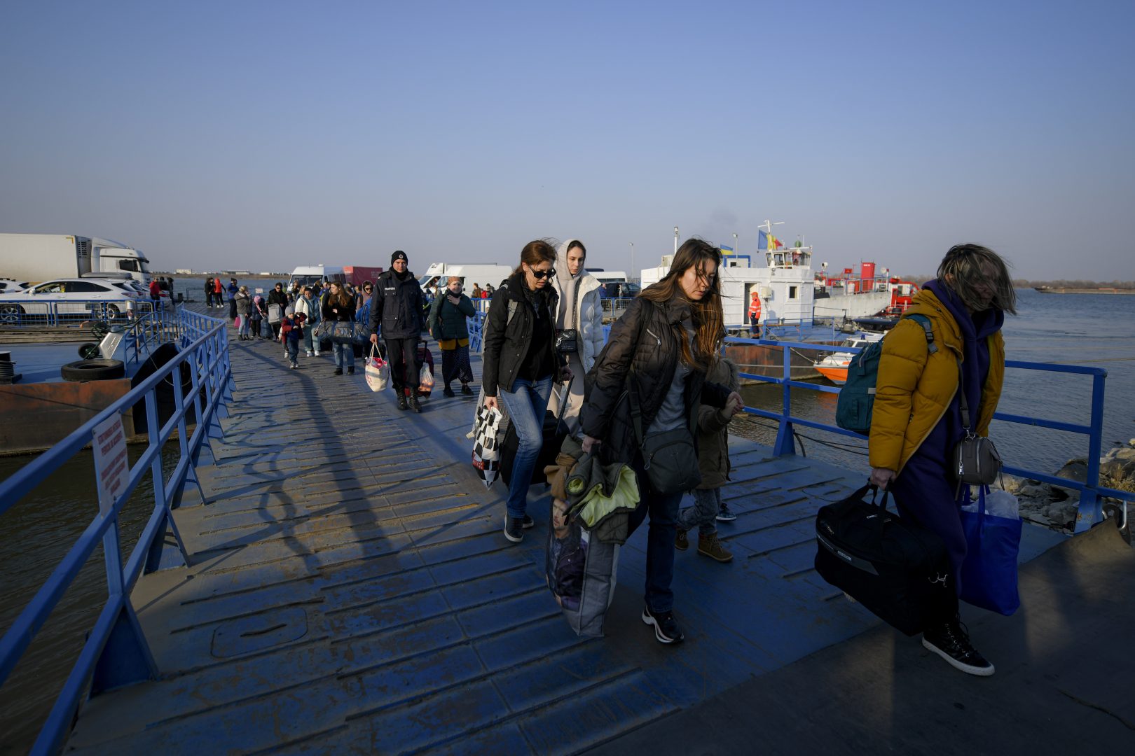 Refugees fleeing the war from neighbouring Ukraine walk after crossing the border by ferry at the Isaccea-Orlivka border crossing in Romania, Thursday, March 24, 2022. (AP Photo/Andreea Alexandru)