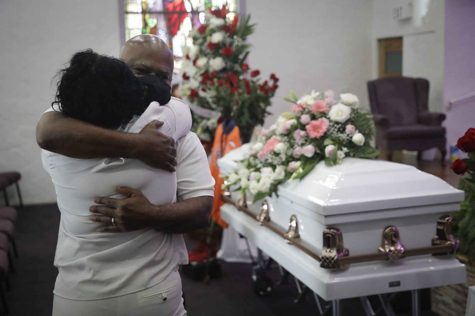 FILE - Darryl Hutchinson, facing camera, is hugged by a fellow relative during a funeral service for Lydia Nunez, who was Hutchinson's cousin, Tuesday, July 21, 2020, at the Metropolitan Baptist Church in Los Angeles. Nunez died from COVID-19.