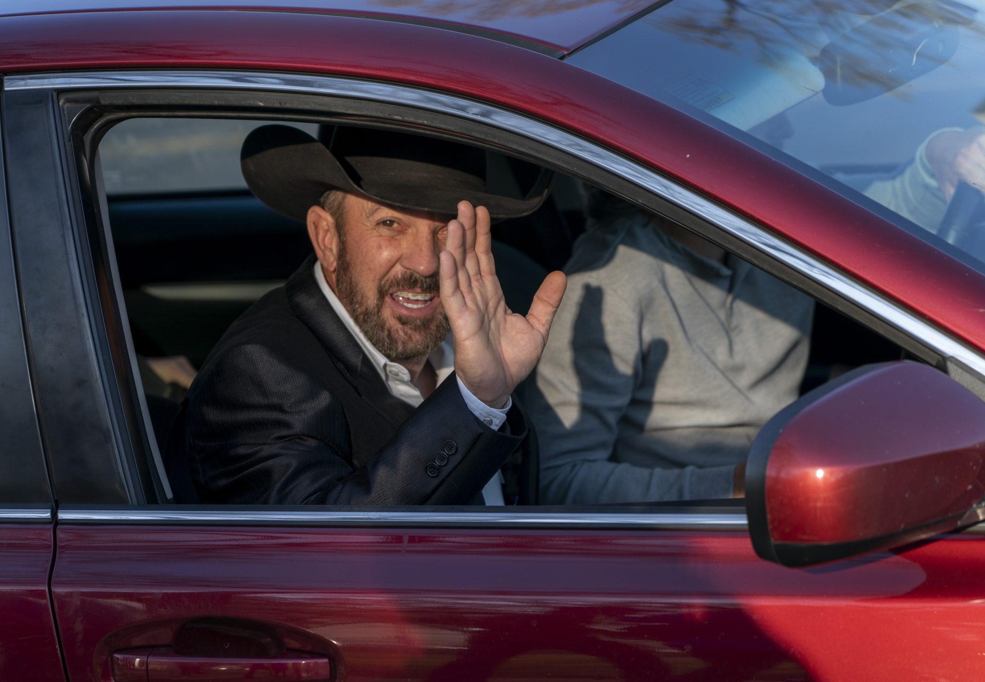 Otero County Commissioner Couy Griffin waves from a car as he leaves federal court in Washington, Monday, March. 21, 2022.