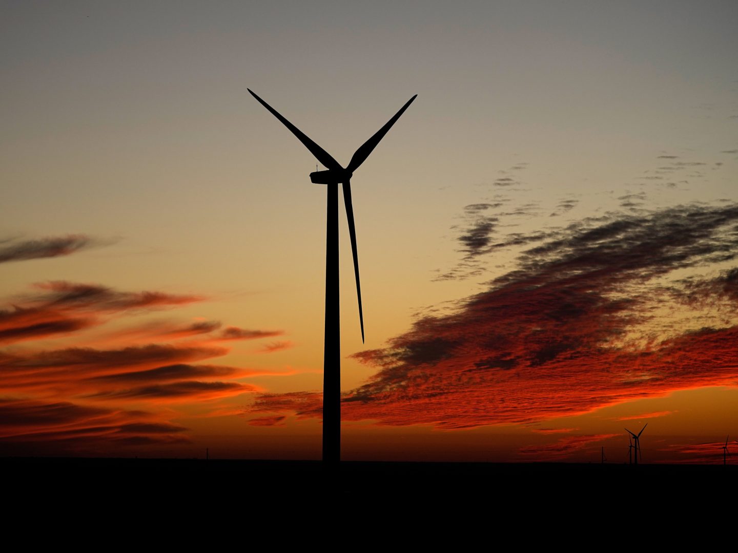 A wind turbine is silhouetted against the sky at sunset Friday, Dec. 17, 2021, near Ellsworth, Kan. The 300-foot-tall turbine is among the 134 units comprising the Post Rock Wind Farm. 