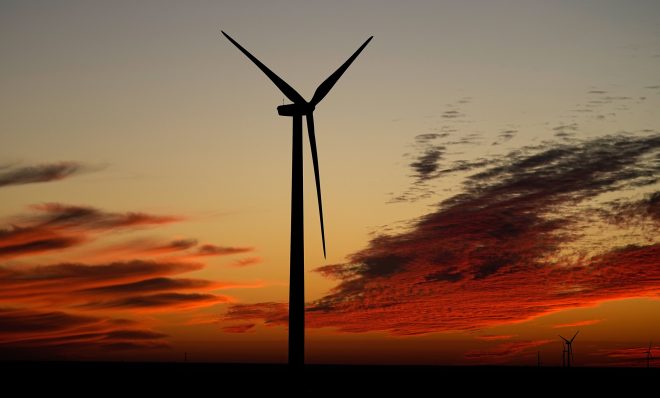 A wind turbine is silhouetted against the sky at sunset Friday, Dec. 17, 2021, near Ellsworth, Kan. The 300-foot-tall turbine is among the 134 units comprising the Post Rock Wind Farm. 