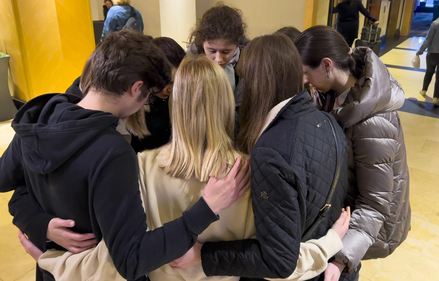 Mariia Pachenko, top center, huddles with Ukrainian peers in prayer on April 8, 2022, as the group disbands after spending nearly a week together taking part in the National Model United Nations Conference in New York. (AP Photo/Bobby Caina Calvan)