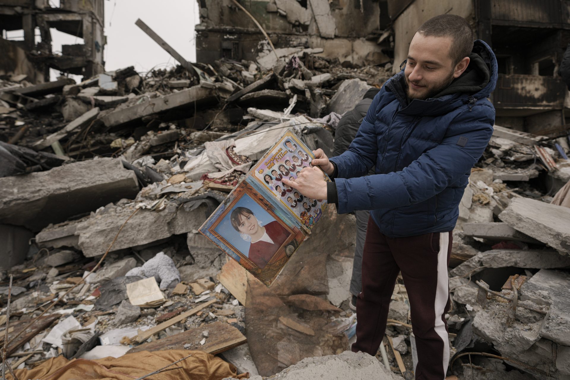 Dmitriy Evtushkov, 25, points to his picture in a primary school album retrieved from the rubble of an apartment building destroyed during fighting between Ukrainian and Russian forces in Borodyanka, Ukraine, Tuesday, April 5, 2022.