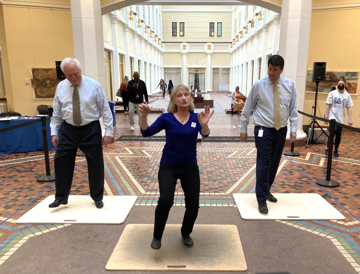From left in back row, Rep. Lee James (R-Venango) and Rep. Joe Cerisi (D-Montgomery) take a tap-dancing lesson while rallying on April 26 in Harrisburg for their bill aimed at streamlining the dance teacher certification process.