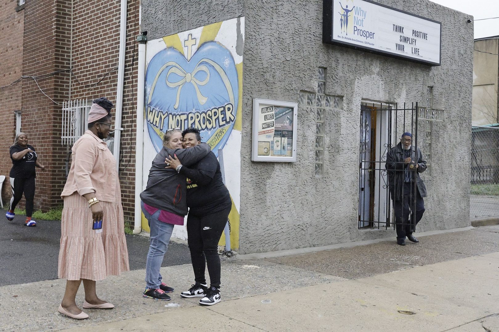 Penny Martin (left) and the Rev. Michelle Simmons, founder and executive director of Why Not Prosper, hug outside of a recovery home in Philadelphia. Simmons said the new licensing system will 