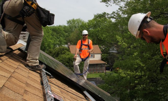 In this photo from 2017, Dennis Hajnik (center) directs a solar panel installation in Bryn Mawr.