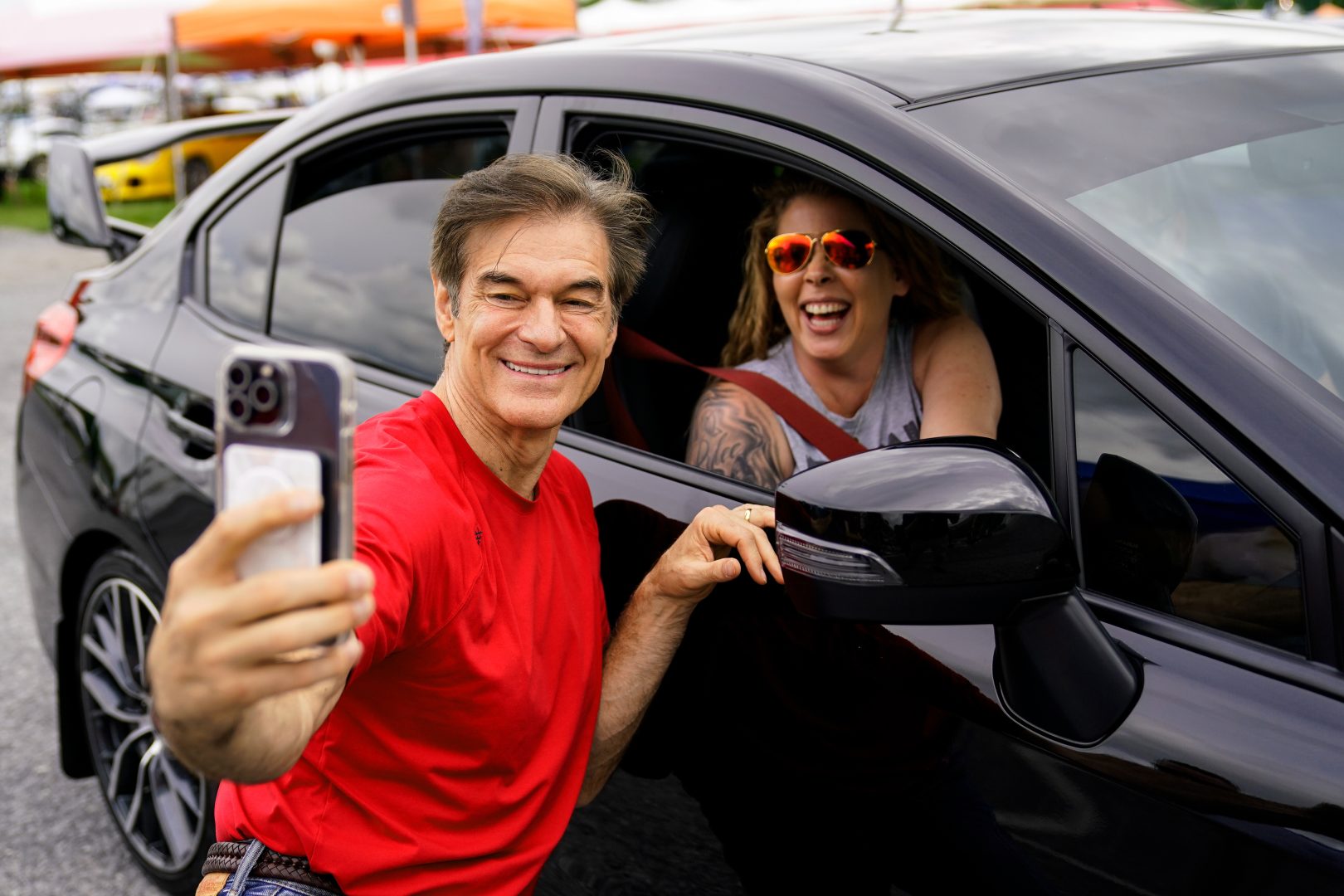 Mehmet Oz, a Republican candidate for U.S. Senate in Pennsylvania, poses for a photograph with an attendee during his visit to a car show in Carlisle, Pa., Saturday, May 14, 2022. (AP Photo/Matt Rourke)