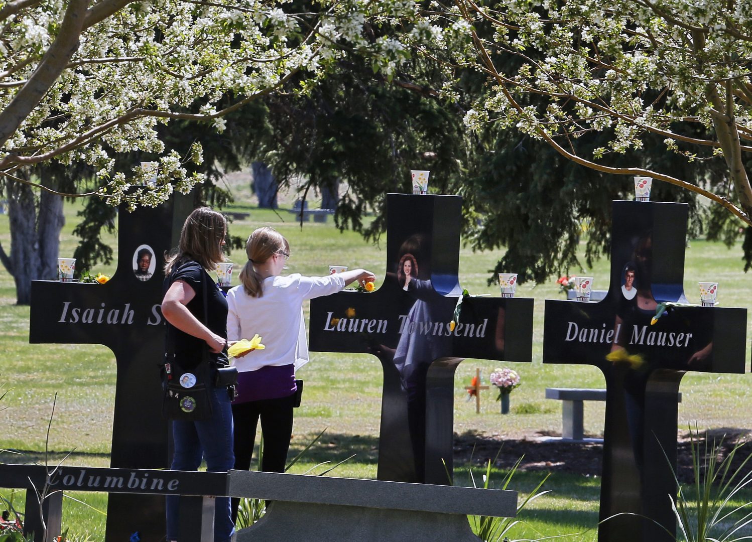 FILE - A family visits the memorial crosses dedicated to the the 13 people killed in the 1999 Columbine High School shooting attack, at Chapel Hill Memorial Gardens in Littleton, Colo., Easter Sunday, April 20, 2014. There have been dozens of shootings and other attacks in U.S. schools and colleges over the years, but until the massacre at Colorado's Columbine High School in 1999, the number of dead tended to be in the single digits. Since then, the number of shootings that included schools and killed 10 or more people has mounted .