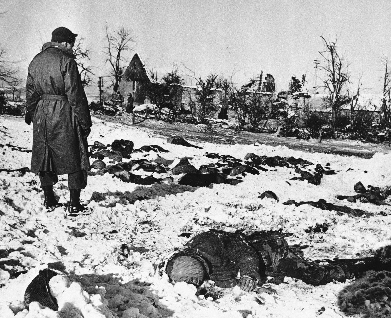 GI looks at corpses of American soldiers killed in Cold Blood by fire from German tank in Belgium on Dec. 17, 1944 after they had been captured. 