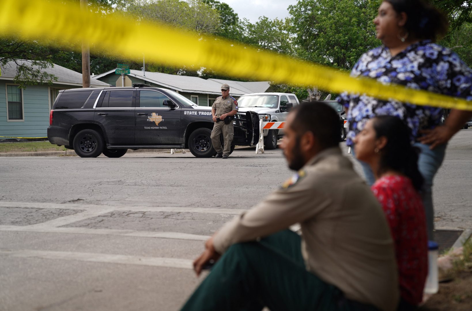 TOPSHOT - People sit on the curb outside of Robb Elementary School as State troopers guard the area in Uvalde, Texas, on May 24, 2022. - An 18-year-old gunman killed 14 children and a teacher at an elementary school in Texas on Tuesday, according to the state's governor, in the nation's deadliest school shooting in years. 