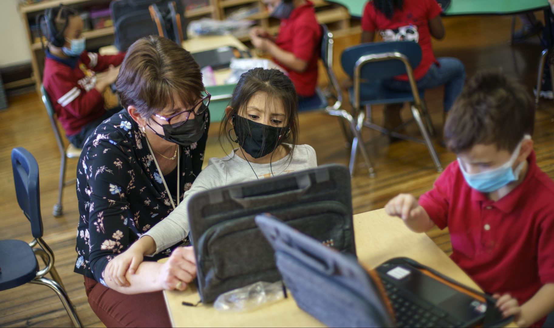 Kindergarten teacher Karen Drolet, left, works with a student at Raices Dual Language Academy, a public school in Central Falls, R.I., Feb. 9, 2022. 