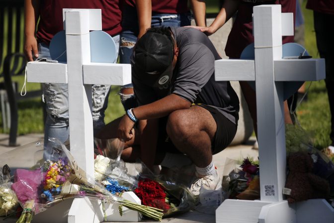 People pay their respects at a memorial site for the victims killed in this week's elementary school shooting in Uvalde, Texas, Thursday, May 26, 2022.
