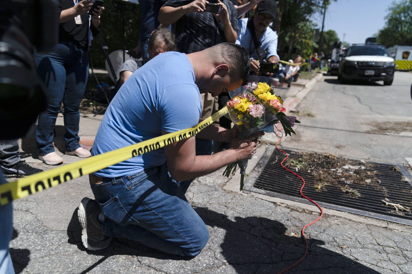 Joseph Avila, left, prays while holding flowers honoring the victims killed in Tuesday's shooting at Robb Elementary School in Uvalde, Texas, Wednesday, May 25, 2022.  