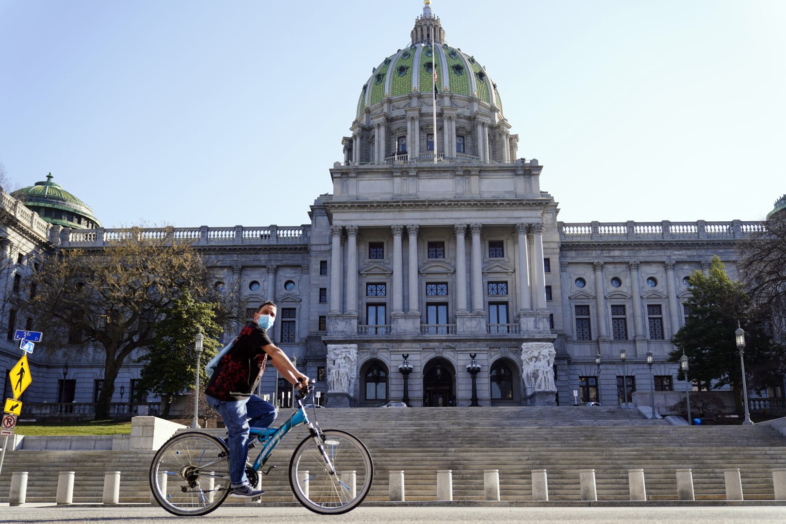 FILE - A cyclist rides past the Pennsylvania Capitol in Harrisburg, Pa., on March 22, 2021. Republican state lawmakers may soon decide which among the scores of potential amendments to the Pennsylvania Constitution will have any shot of making it to a voter referendum — a tactic that can get politically divisive policies around Democratic Gov. Tom Wolf's much-used veto pen. The comparatively large number of proposals pending in the General Assembly address topics that range from voting rights to abortion and real estate taxes. (AP Photo/Matt Rourke, File)