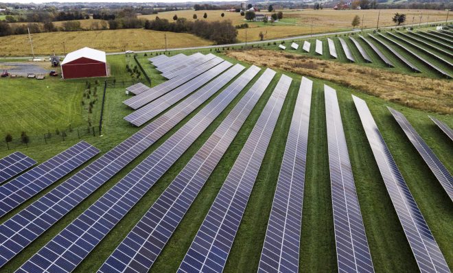 FILE - Farmland is seen with solar panels from Cypress Creek Renewables, Oct. 28, 2021, in Thurmont, Md. President Joe Biden plans to invoke the Defense Production Act to increase U.S. manufacturing of solar panels while declaring a two-year tariff exemption on panels from Southeast Asia. 