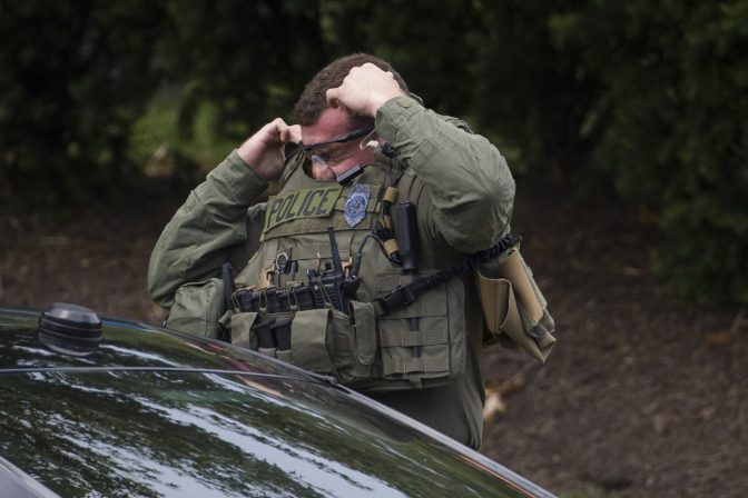 A Fairfax Police tactical officer puts on his body armor near the building that houses Gannett and USA Today, Wednesday, Aug. 7, 2019, in McLean, Va.