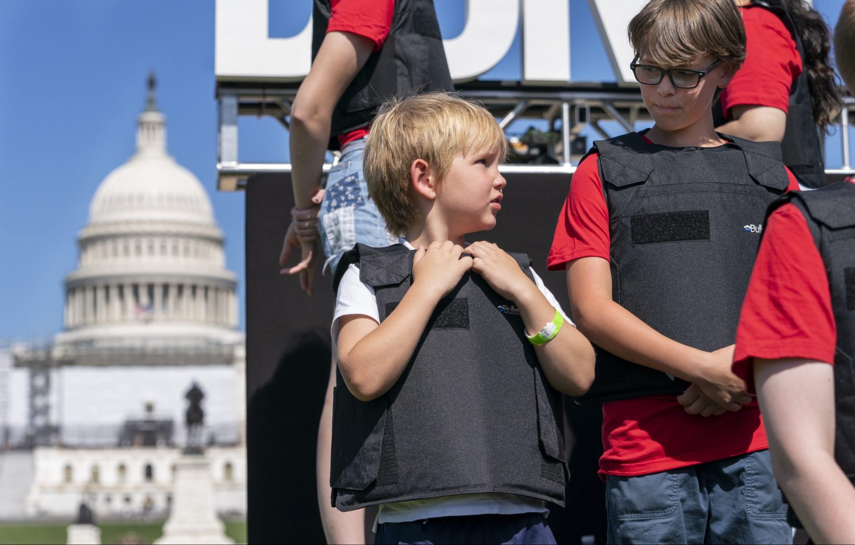 Wearing body armor, Jacob Kelly, 6, talks with Cal Neaville, 11, right, during a gun safety reform rally, Monday, June 6, 2022, outside the U.S. Capitol in Washington. 