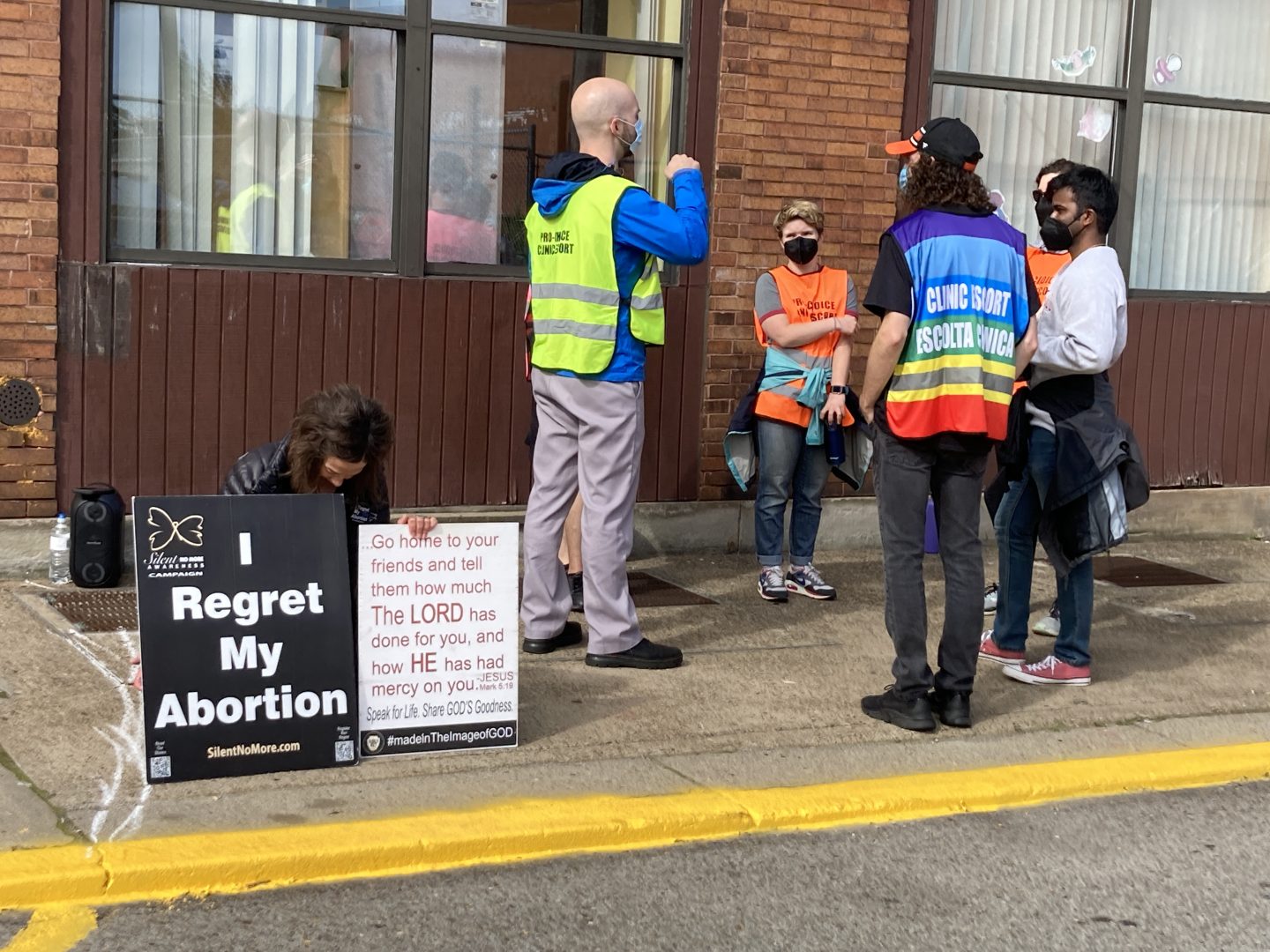 An abortion-rights opponent kneels next to a group of volunteer clinic escorts outside Allegheny Reproductive Health Center, located in Pittsburgh's East Liberty neighborhood.
