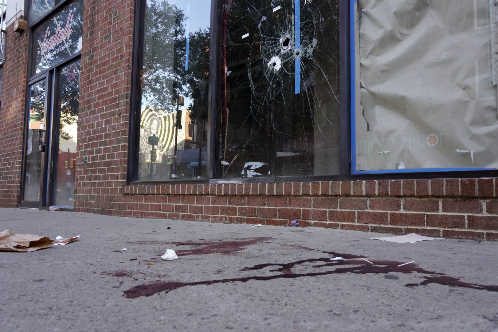  Blood is seen at the scene of a fatal overnight shooting on South Street in Philadelphia, Sunday, June 5, 2022, where bullet holes on a storefront window from a prior shooting can also be seen. 