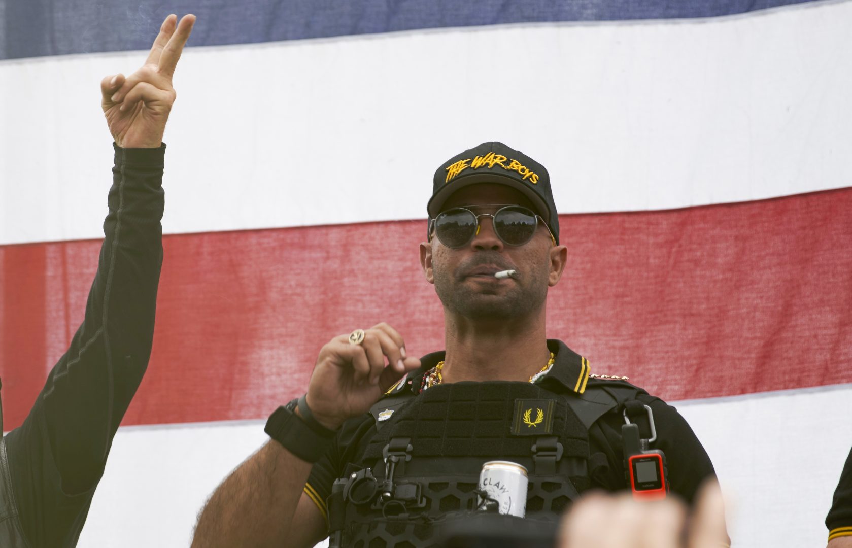 Proud Boys leader Enrique Tarrio wears a hat that says The War Boys and smokes a cigarette at a rally in Delta Park on Sept. 26, 2020, in Portland, Ore.