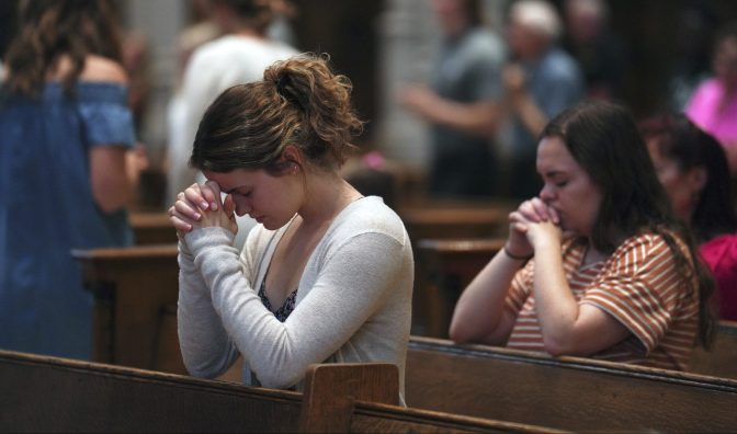 University of Pittsburgh student Olivia Meholic, front, prays after receiving Communion at St. Paul Catholic Cathedral in Pittsburgh on Sunday, June 26, 2022.