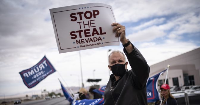 Supporters of President Donald Trump hold signs as they stand outside of the Clark County Elections Department in North Las Vegas, Nev. on Nov. 7, 2020.