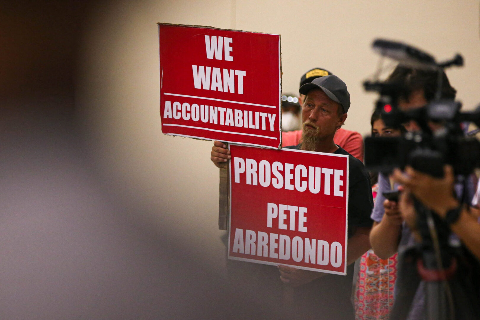 Michael Brown, an Uvalde community member who has a child that was enrolled ar Robb Elementary, holds signs calling for police accountability during a hearing by a Texas House Investigative Committee at the SSGT Willie de Leon Civic Center in Uvlade, Texas, U.S. July 17, 2022.