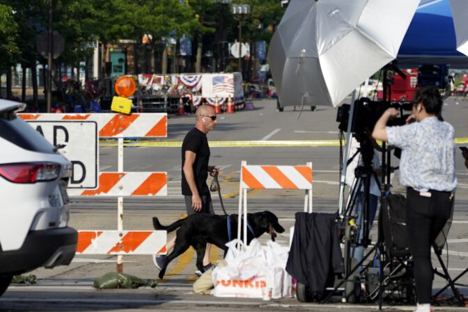 A Highland Park, Ill., resident walks his dog past a barricade and in front of television crews one day after a mass shooting in the northern Chicago suburb Tuesday, July 5, 2022.