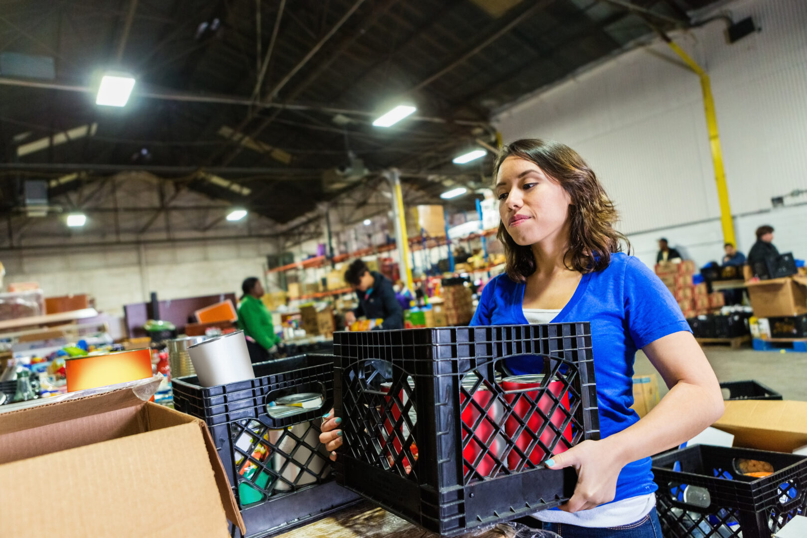 A young woman volunteers to organize donations at a large food bank
