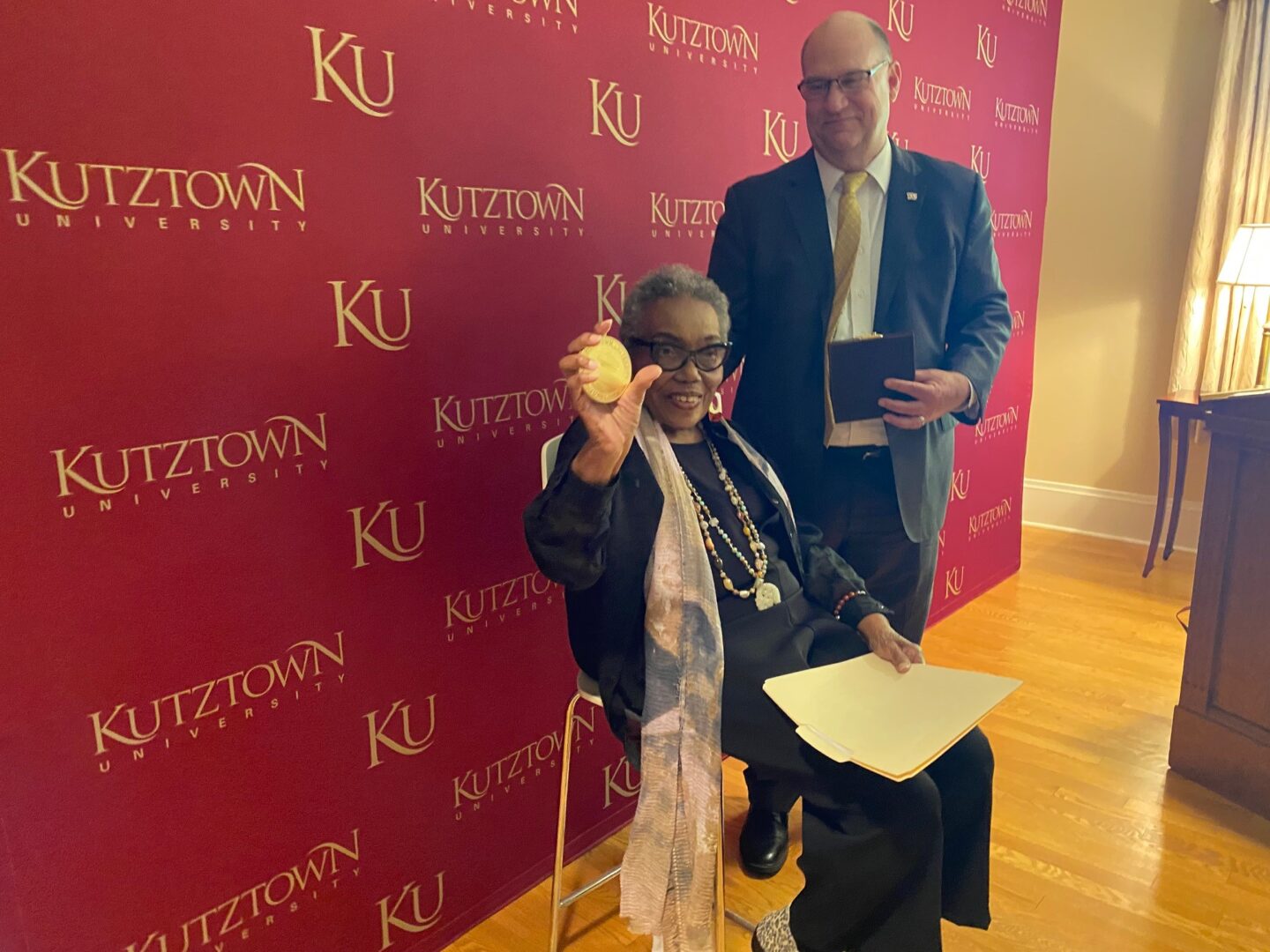 Bessie Reese Crenshaw holds up the Presidents Medal awarded to her bu Kutztown University president  Kenneth S. Hawkins