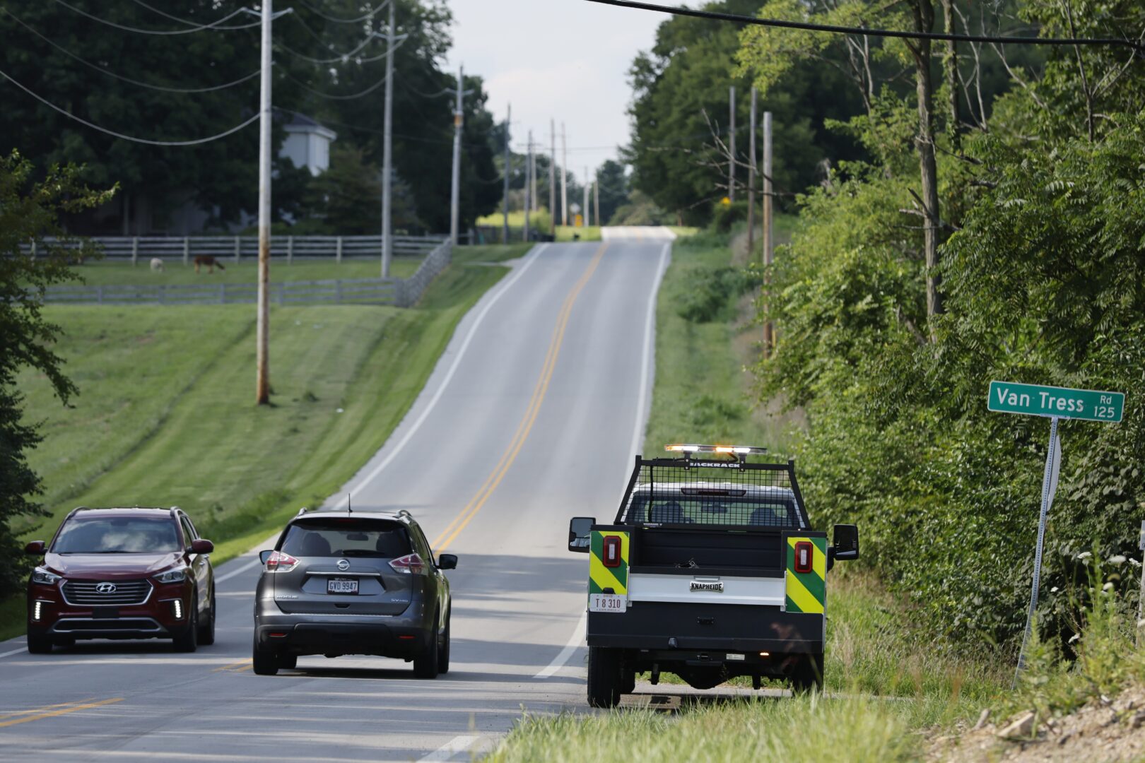 Clinton County employees sit in their vehicles blocking the road that leads to the scene where an armed man was shot and killed by police after breaching the FBI's Cincinnati field office Thursday, Aug. 11, 2022, in Wilmington, Ohio. 