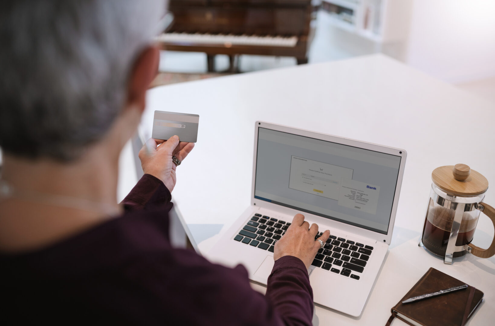 Pensioner holding credit card for internet banking and entering in security details. Senior woman making online payments using laptop. Mature woman shopping online with credit card.