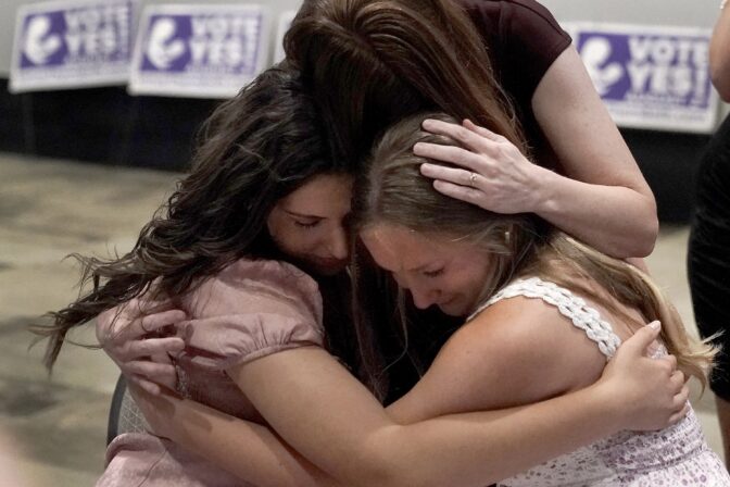 Hannah Joerger, left, Amanda Grosserode, center, and Mara Loughman hug after a Value Them Both watch party after a question involving a constitutional amendment removing abortion protections from the Kansas constitution failed, Tuesday, Aug. 2, 2022, in Overland Park, Kan.