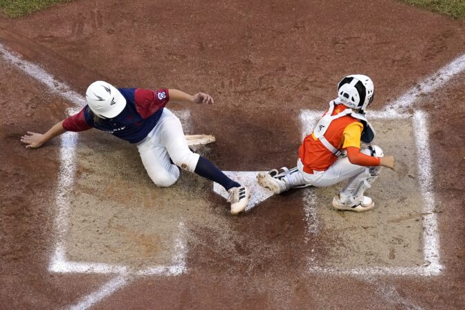 Hollidaysburg, Pa.'s Chase Link, left, scores behind Pearland, Texas catcher Ford Hill during the first inning of a baseball game at the Little League World Series in South Williamsport, Pa., Wednesday, Aug. 24, 2022. Texas won 8-4.