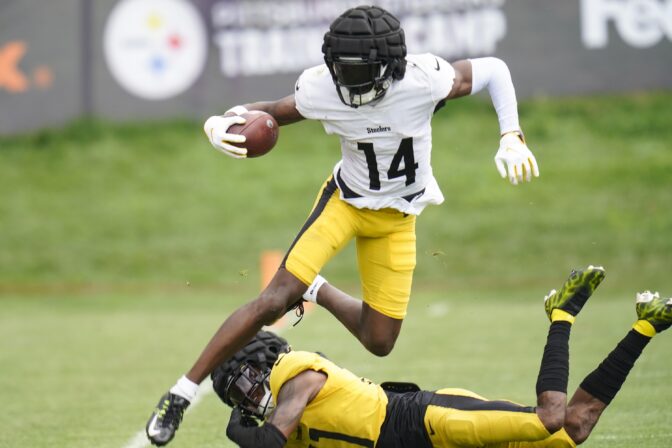 Pittsburgh Steelers wide receiver George Pickens (14) leaps over defensive back Justin Layne in a drill during practice at NFL football training camp in Latrobe, Pa., Thursday, Aug. 11, 2022.