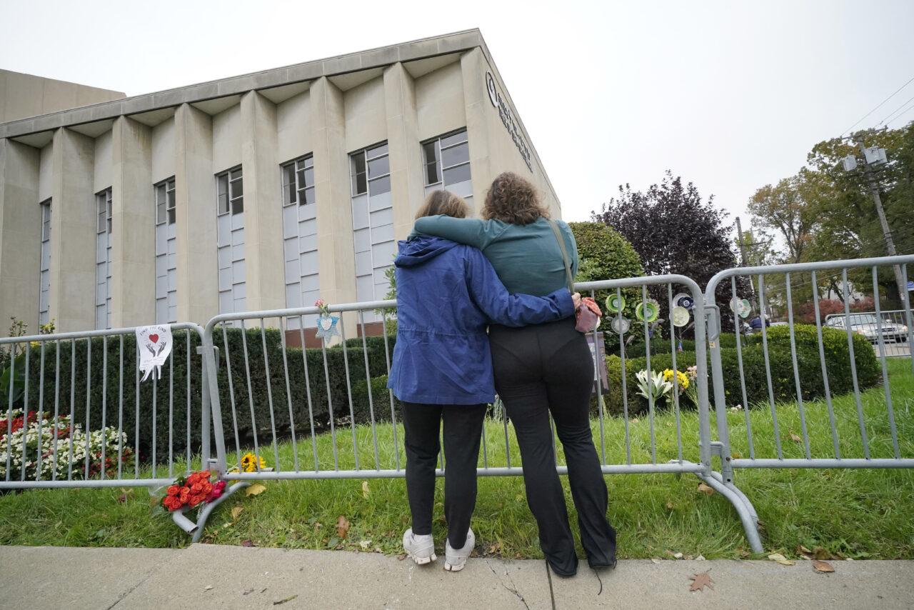 FILE - Two women pause along a fence outside the dormant landmark Tree of Life synagogue in Pittsburgh's Squirrel Hill neighborhood on Wednesday, Oct. 27, 2021.   The long-delayed capital murder trial of Robert Bowers in the 2018 Pittsburgh synagogue massacre will begin in April, 2023 a federal judge has ruled. (AP Photo/Gene J. Puskar, File)