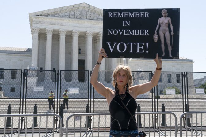 Nicky Sundt, of Washington, holds a sign with an image depicting Medusa that says, "Remember in November, Vote!," outside of the Supreme Court, June 29, 2022, in Washington.