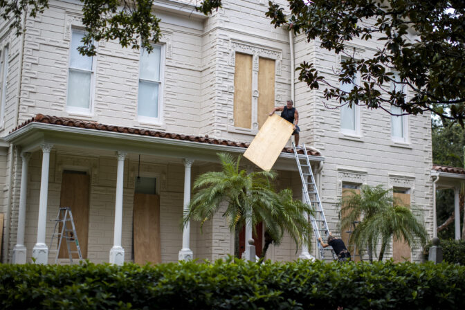 Two people work on boarding up a house in South Tampa Bay Florida before Hurricane Ian