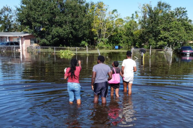 Residents wade through water to get to their house in a flooded neighborhood following Hurricane Ian on October 1, 2022 in Orlando, Florida.