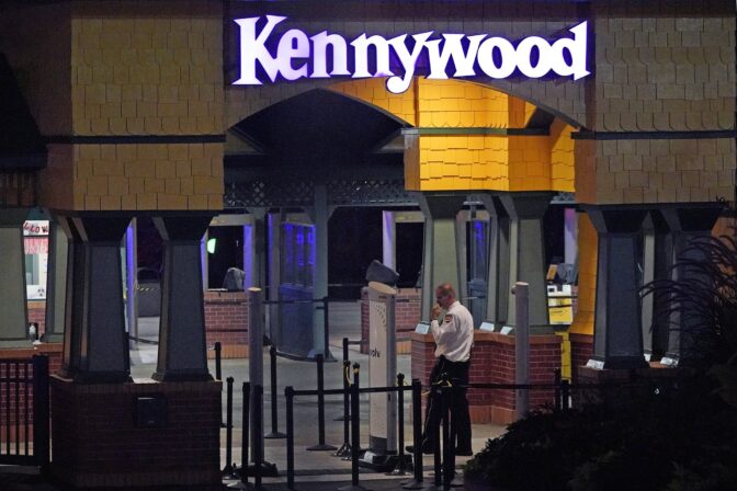 A Kennywood Park security guard stands at the main entrance to the amusement park in West Mifflin, Pa., early Sunday, Sept 25, 2022. Pennsylvania police and first responders have descended on the amusement park southeast of Pittsburgh following reports of shots fired inside the attraction, which was kicking off a Halloween-themed festival.